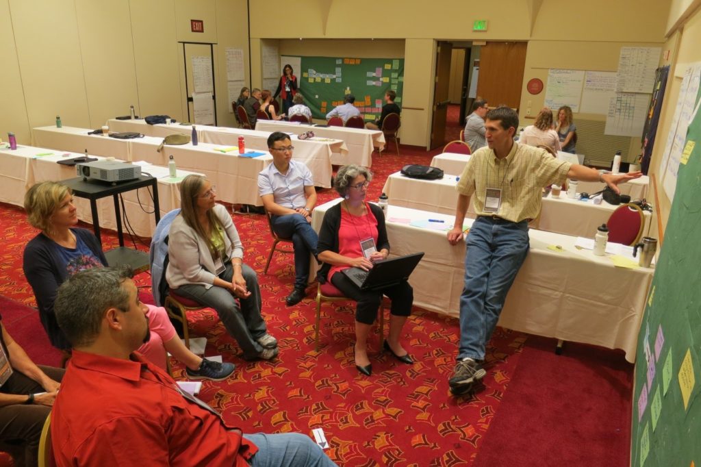 Three break-out groups in action. Arlyne Johnson (standing in back of room), Quinn Shurtliff (standing in front), and Jim Goetz (taking the picture) led these groups.